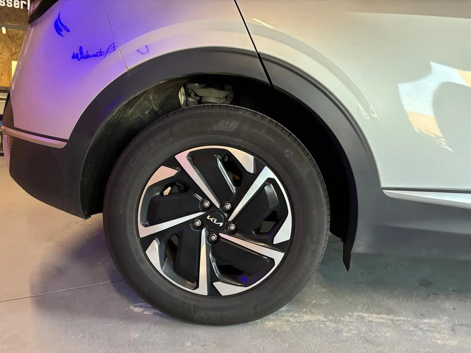 Gros plan sur la roue arrière droite grise d’un Kia Sportage 2024 hybride avec jante alliage bicolore distinctive.