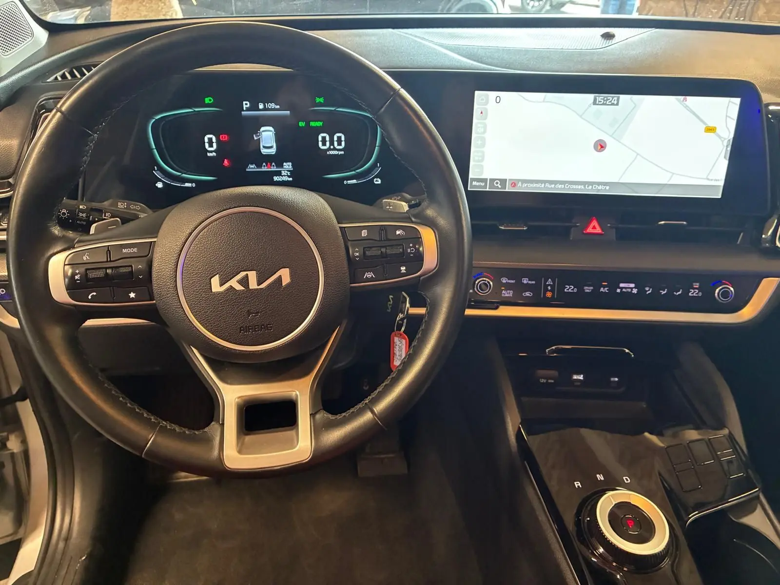 Vue intérieure du poste de conduite du Kia Sportage hybride 2024, avec volant cuir, tableau de bord numérique et écran tactile large.