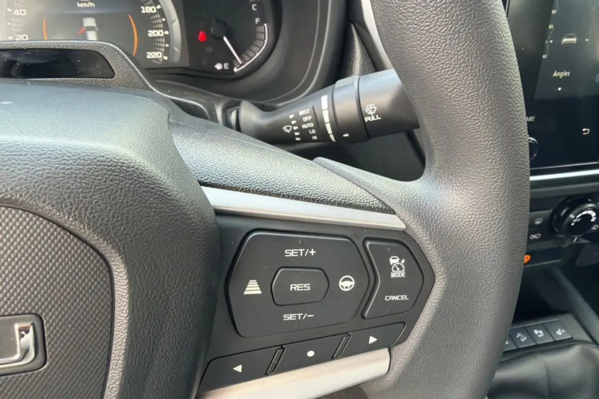 Gros plan sur le volant multifonctions de l'Isuzu D-MAX 2026, avec commandes de régulateur et assistance au pilotage.