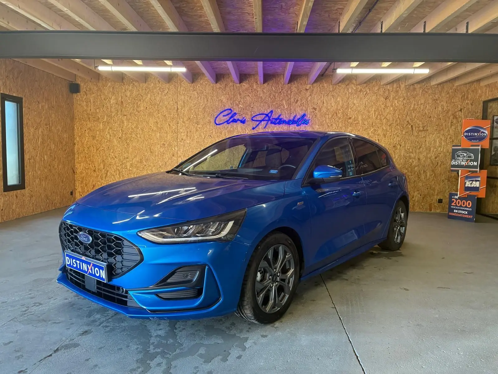 Ford Focus 1.0 EcoBoost bleu en 3/4 avant droit, avec calandre hexagonale et jantes alliage visibles.