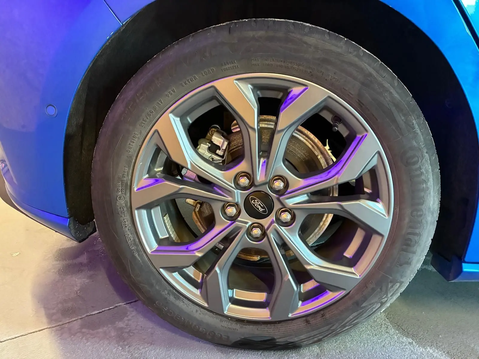 Gros plan sur la roue avant gauche d’une Ford Focus bleu 2024 avec jante alliage et logo Ford au centre.