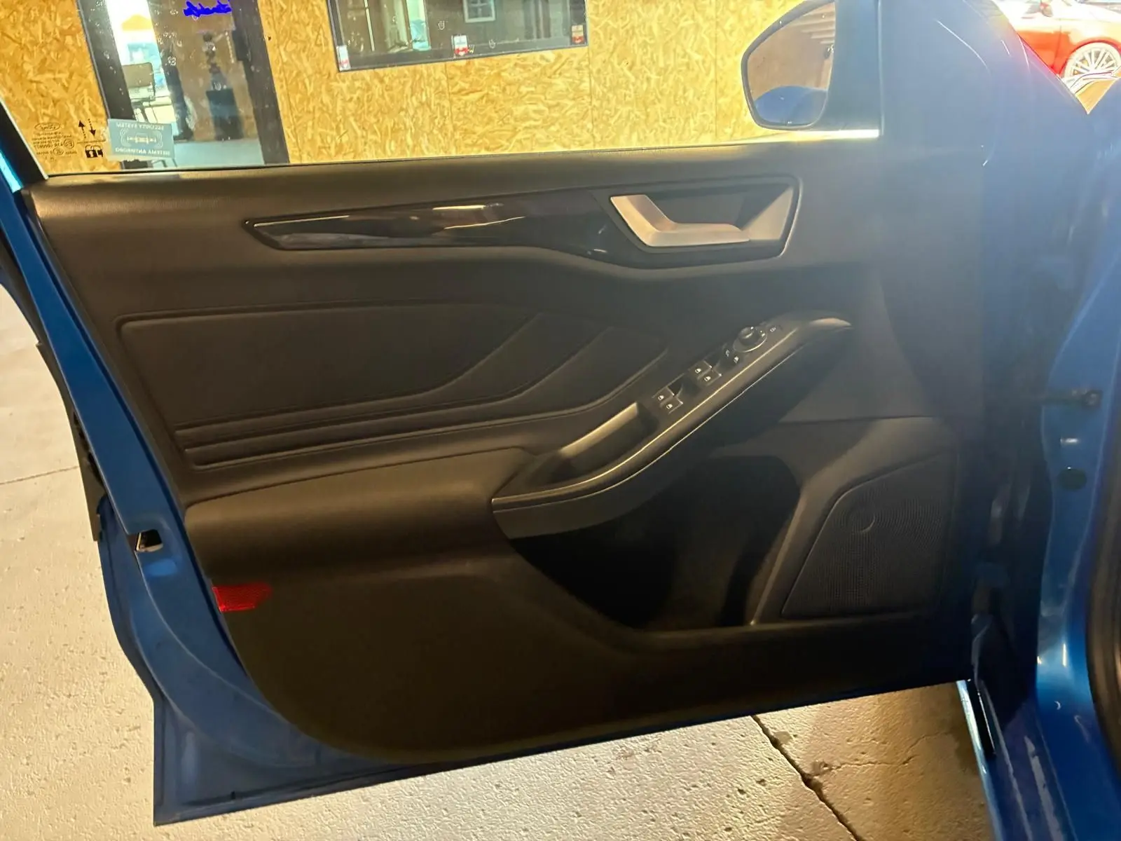 Vue intérieure de la porte avant gauche bleue de la Ford Focus 2024, avec commandes électriques et garniture noire.