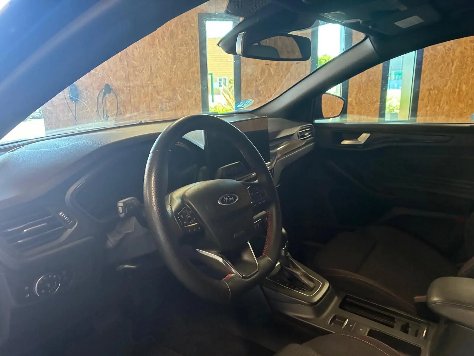 Vue intérieure côté conducteur de la Ford Focus 2024 bleu, volant multifonction et console centrale avec boîte automatique.