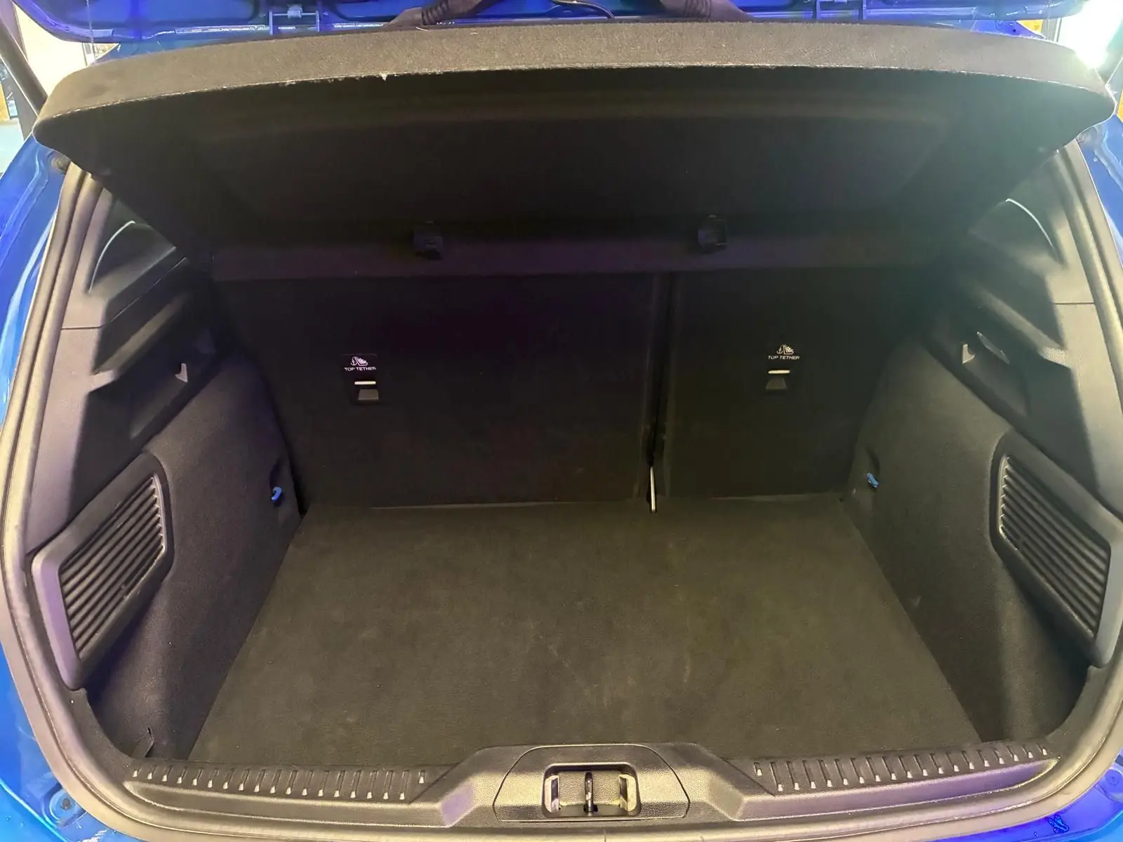Vue intérieure du coffre ouvert d'une Ford Focus bleue 2024, montrant un espace de rangement propre et spacieux.