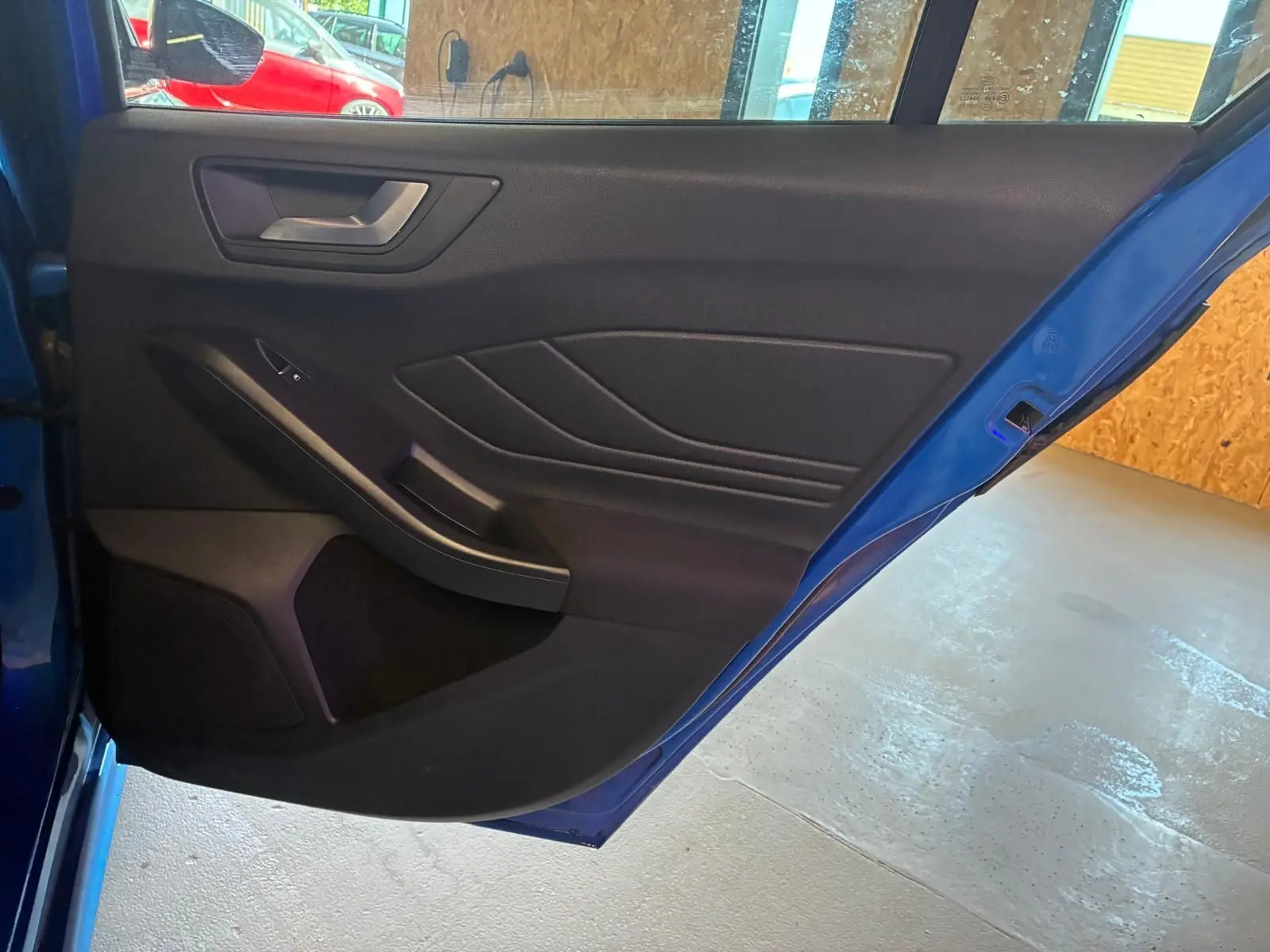 Vue intérieure de la porte arrière droite bleu foncé d’une Ford Focus 2024 avec garniture noire et poignée argentée.