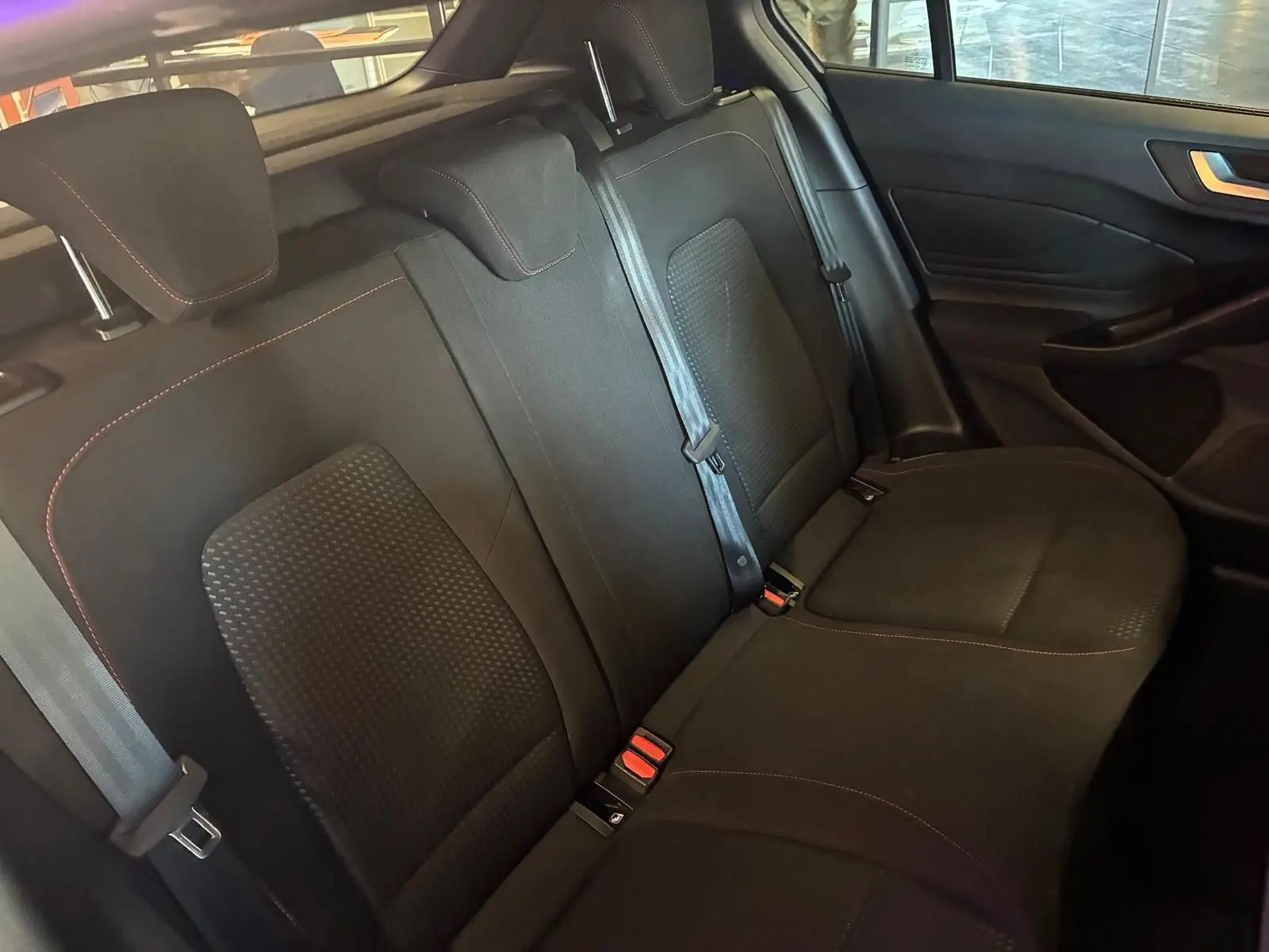 Vue intérieure des sièges arrière en tissu noir avec surpiqûres rouges de la Ford Focus 2024, version ST Line.