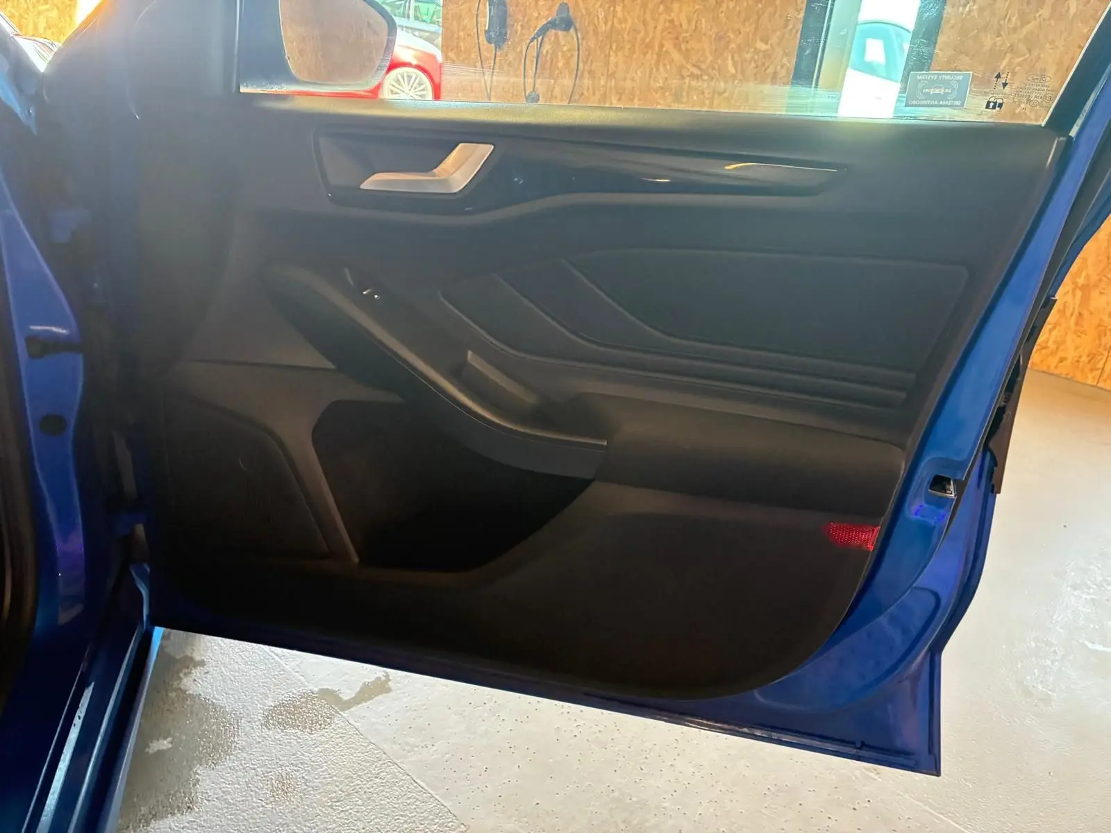 Vue intérieure de la porte avant gauche bleu de la Ford Focus 2024, avec garniture noire et poignée argentée.