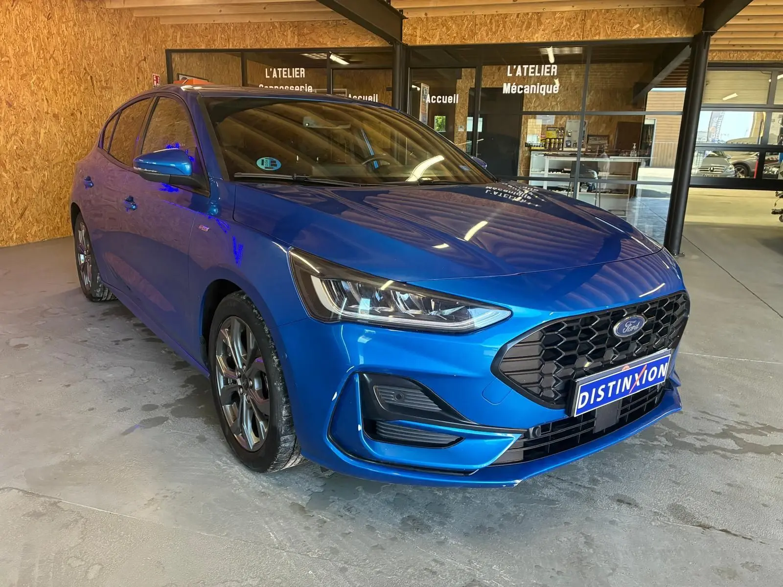 Ford Focus 2024 bleu en vue 3/4 avant droit, avec calandre noire hexagonale et phares LED distinctifs.