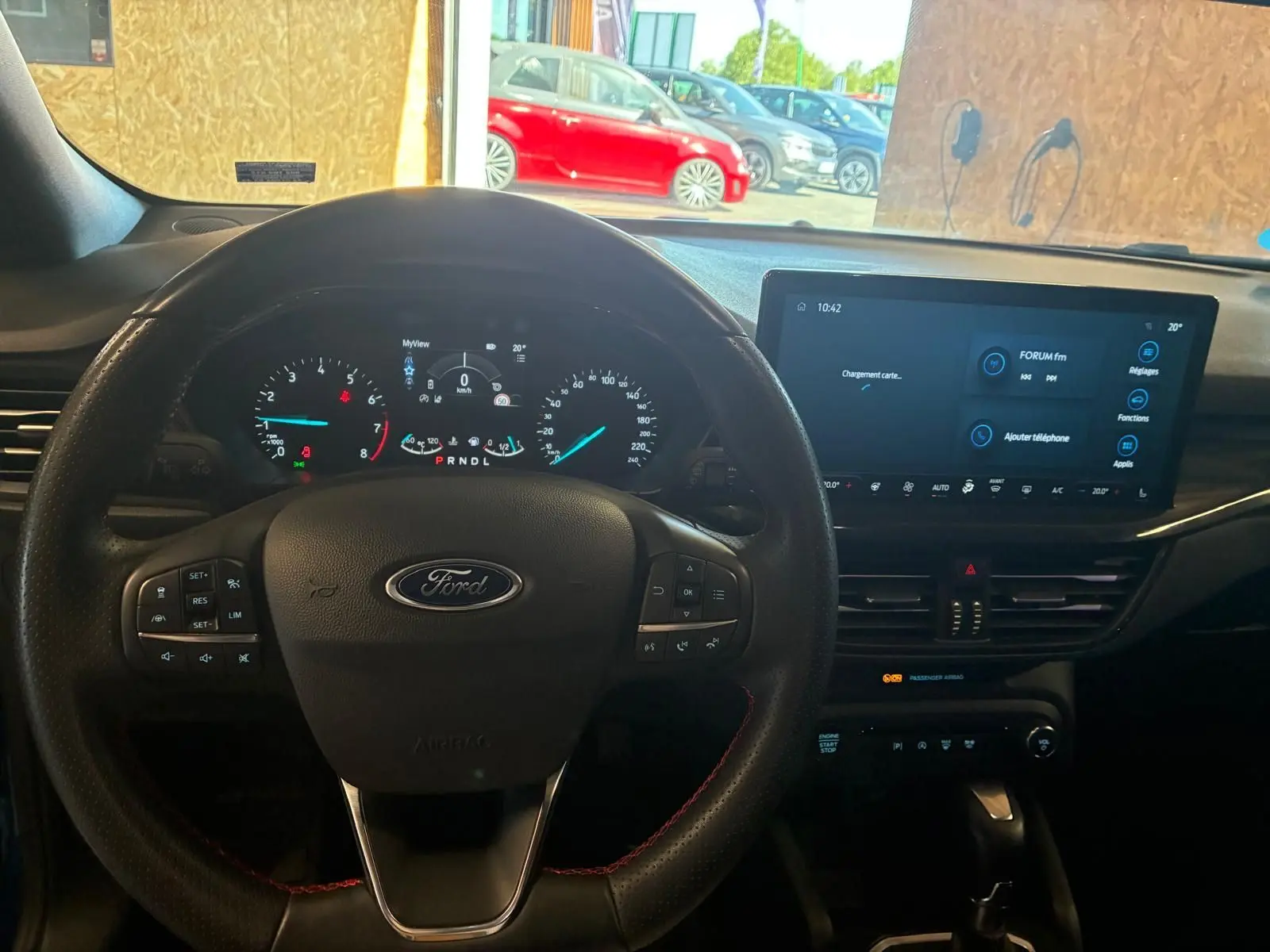 Vue intérieure centrée sur le volant Ford et le tableau de bord numérique d'une Focus 2024, avec écran tactile et commandes au volant.