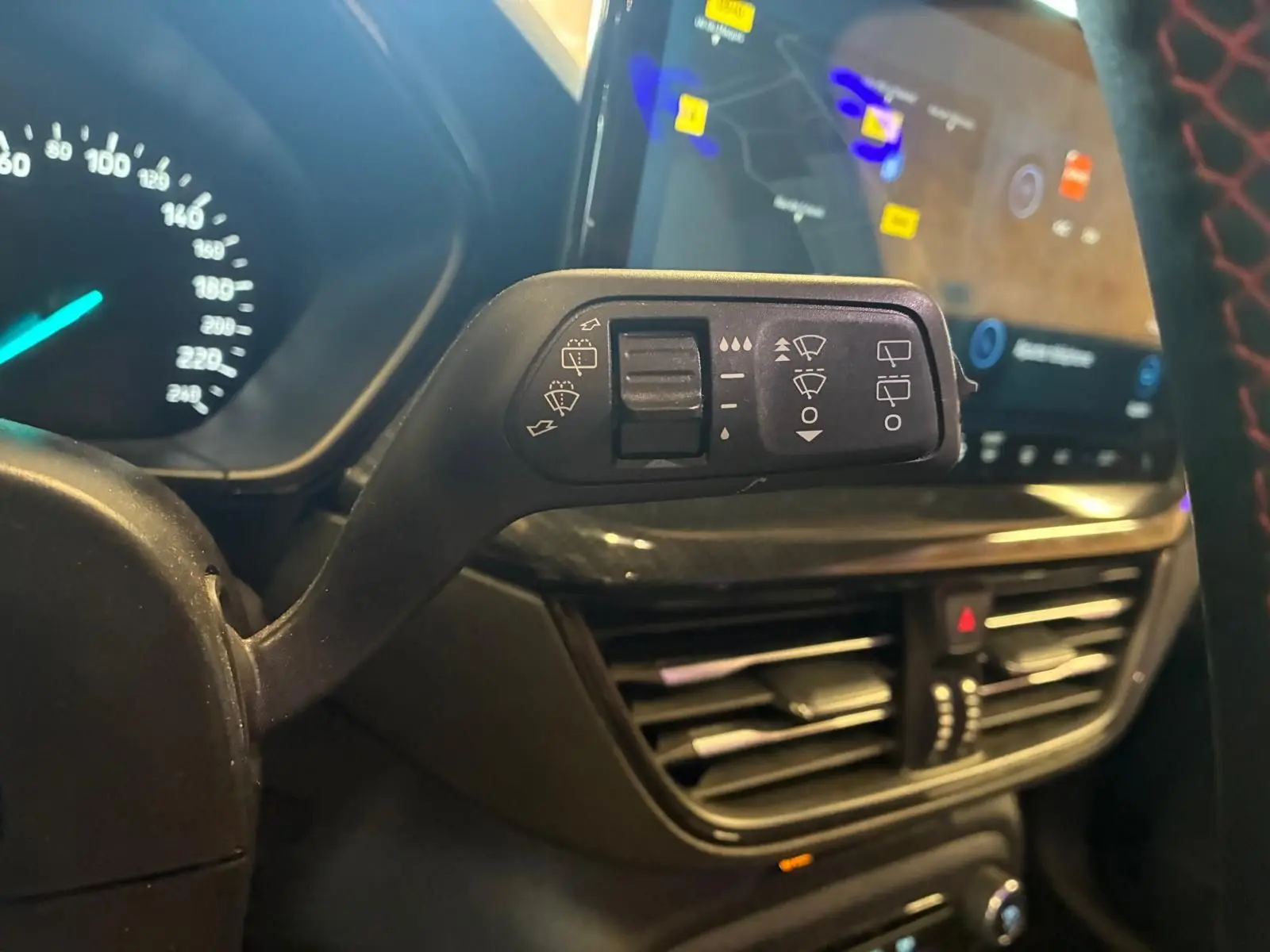 Gros plan sur la commande des essuie-glaces côté gauche dans l’habitacle noir d’une Ford Focus bleue 2024.