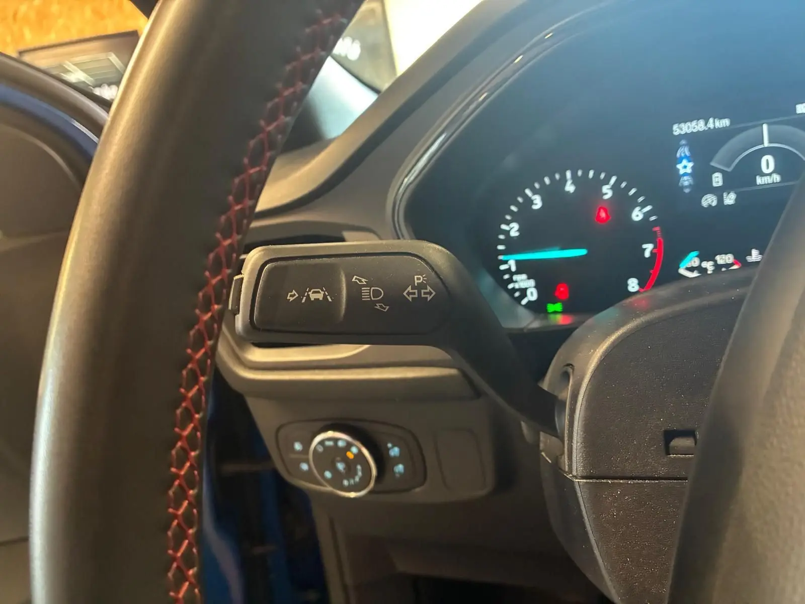Vue intérieure rapprochée du levier de clignotant et du tableau de bord numérique d'une Ford Focus bleue 2024.
