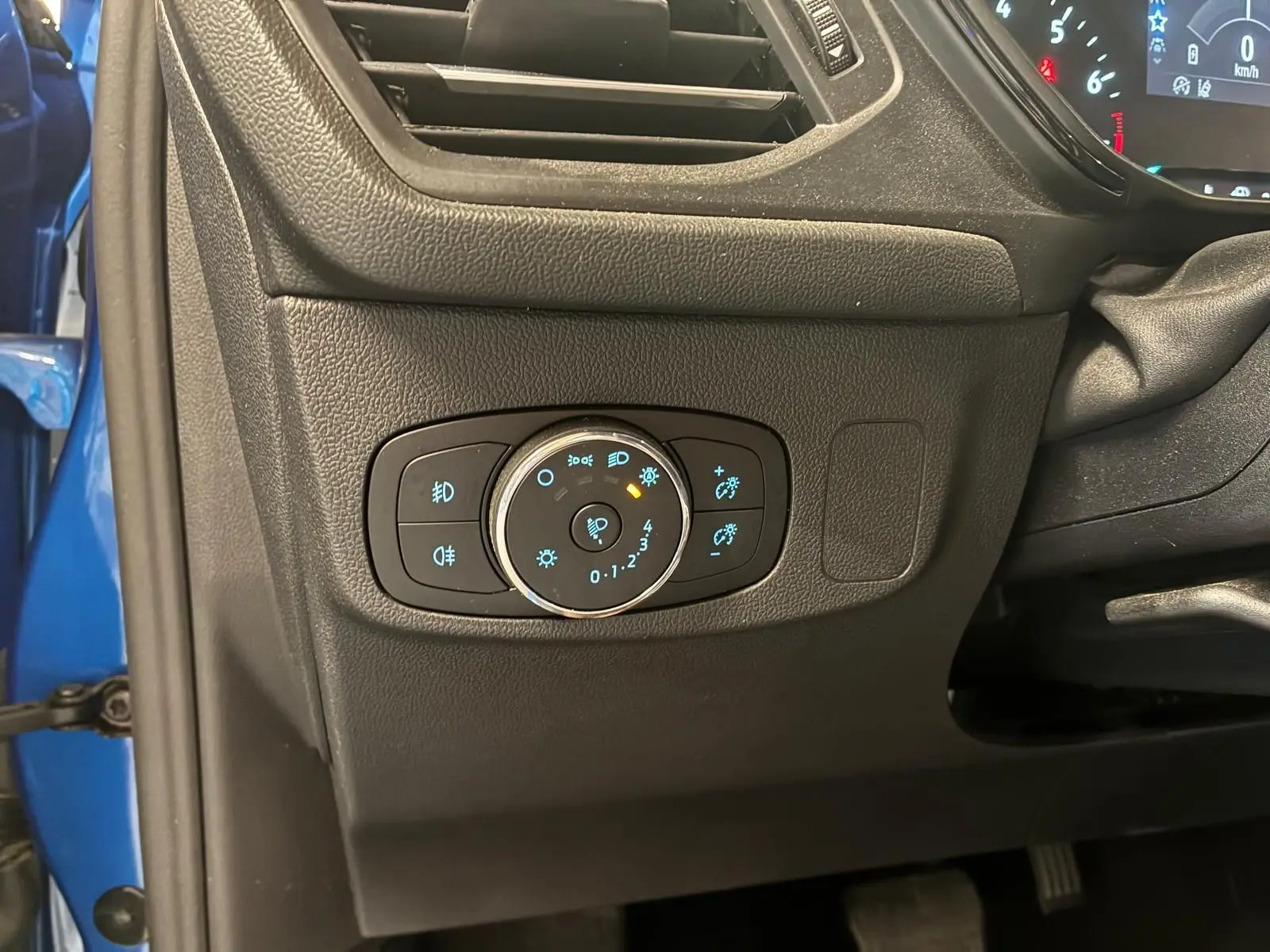Détail du tableau de bord côté gauche d'une Ford Focus bleu 2024, avec commandes d'éclairage et ventilation visibles.