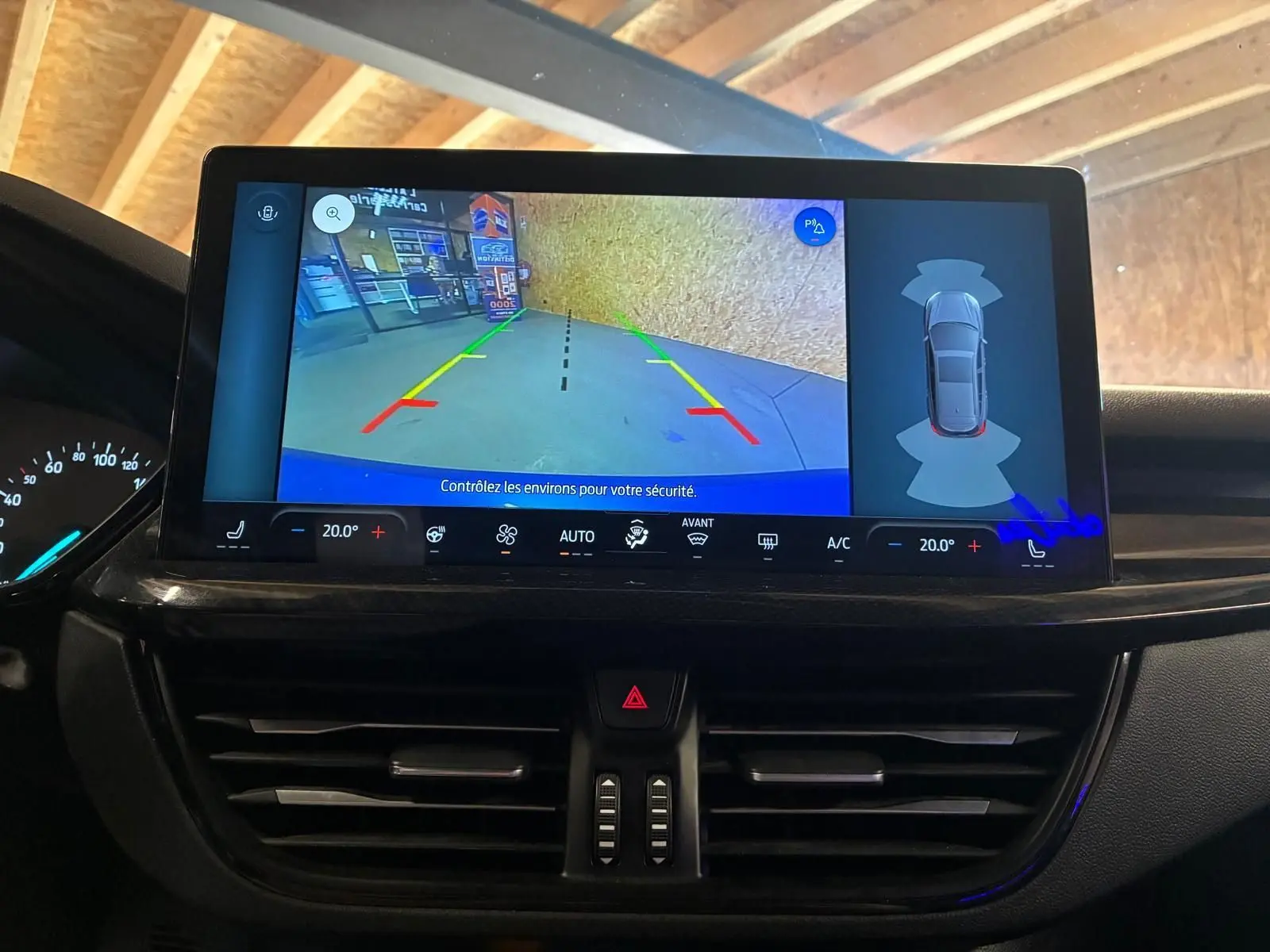 Vue intérieure du tableau de bord de la Ford Focus 2024, écran central affichant la caméra de recul et les commandes climatiques.