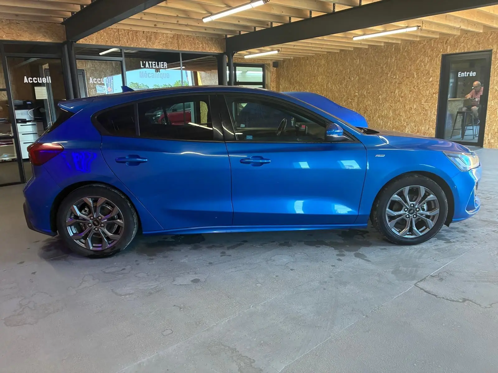 Vue de profil côté gauche d'une Ford Focus 2024 bleu vif, finition ST Line avec jantes alliage et cinq portes.