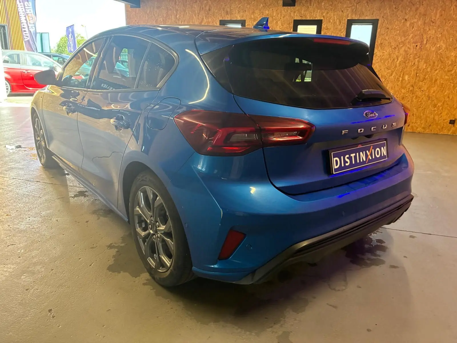 Vue 3/4 arrière droite d'une Ford Focus bleu 2024 avec finition ST Line et feux arrière LED distinctifs.