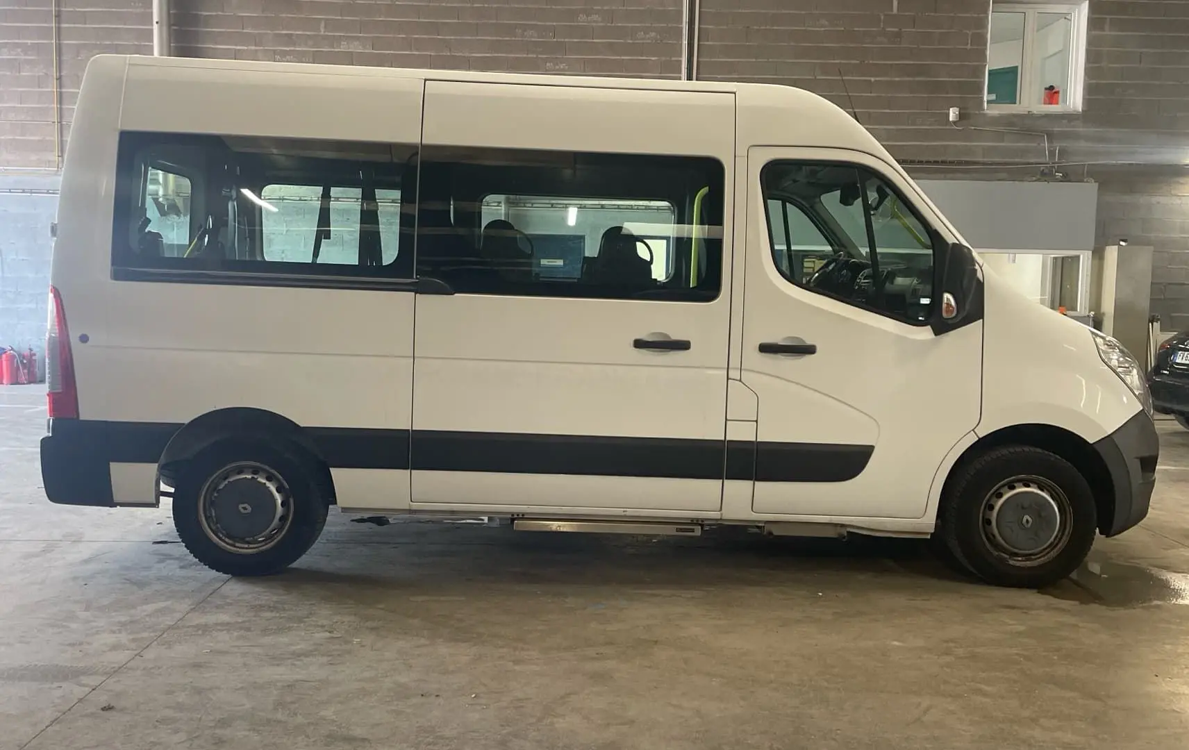 Profil droit d’un Renault Master blanc 2019 avec porte latérale coulissante et marchepied visible en intérieur d’atelier.