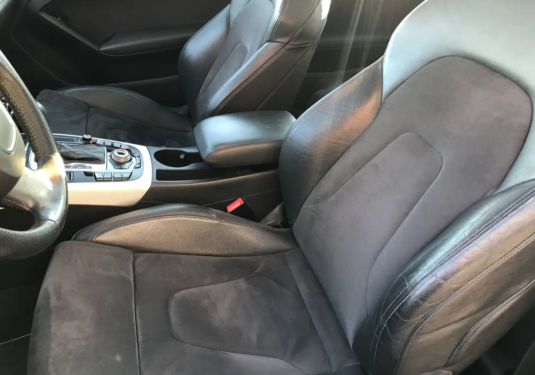 Vue rapprochée des sièges avant en cuir noir et alcantara de l'Audi A5 Coupé gris dauphin, avec console centrale visible.