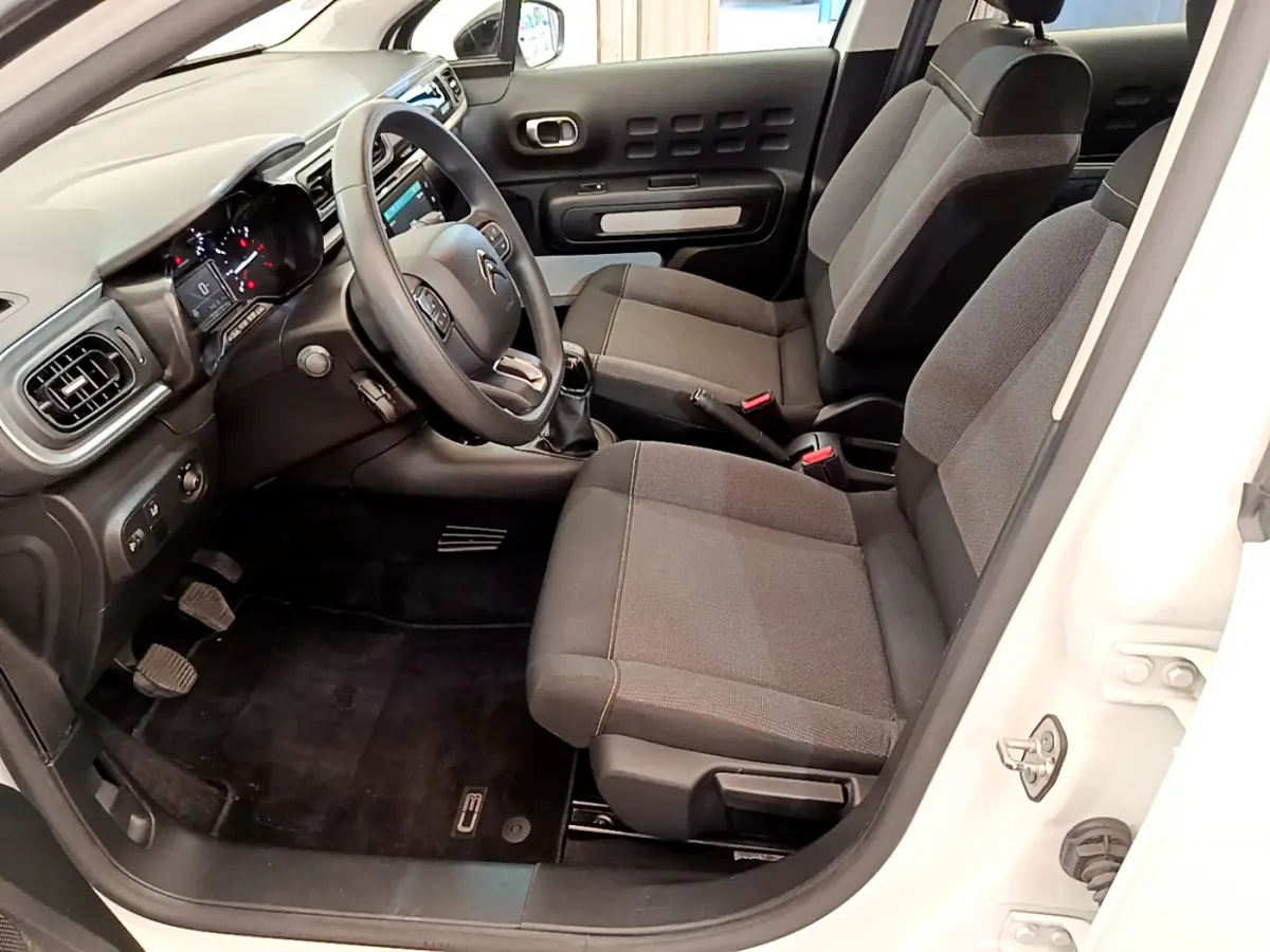 Intérieur côté conducteur de la Citroën C3 blanche 2019, montrant sièges gris et tableau de bord avec écran tactile.
