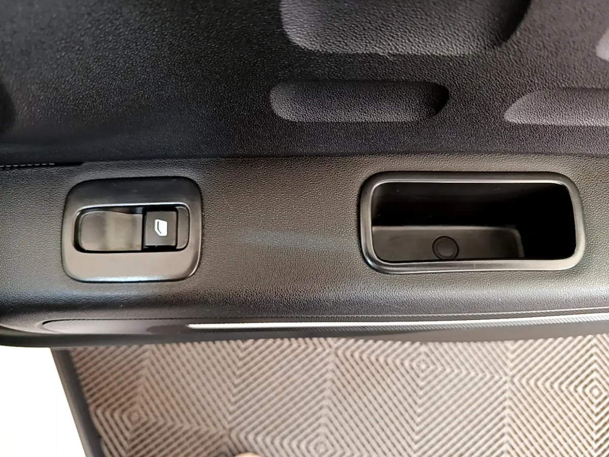Gros plan sur la commande de lève-vitre et poignée intérieure noire côté gauche d'une Citroën C3 blanche 2019.