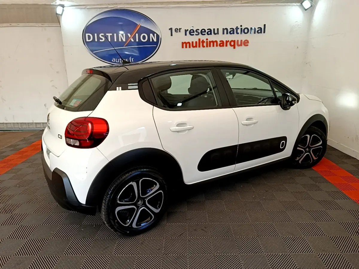 Vue 3/4 arrière droite d'une Citroën C3 blanche 2019 avec toit noir et protections latérales noires.