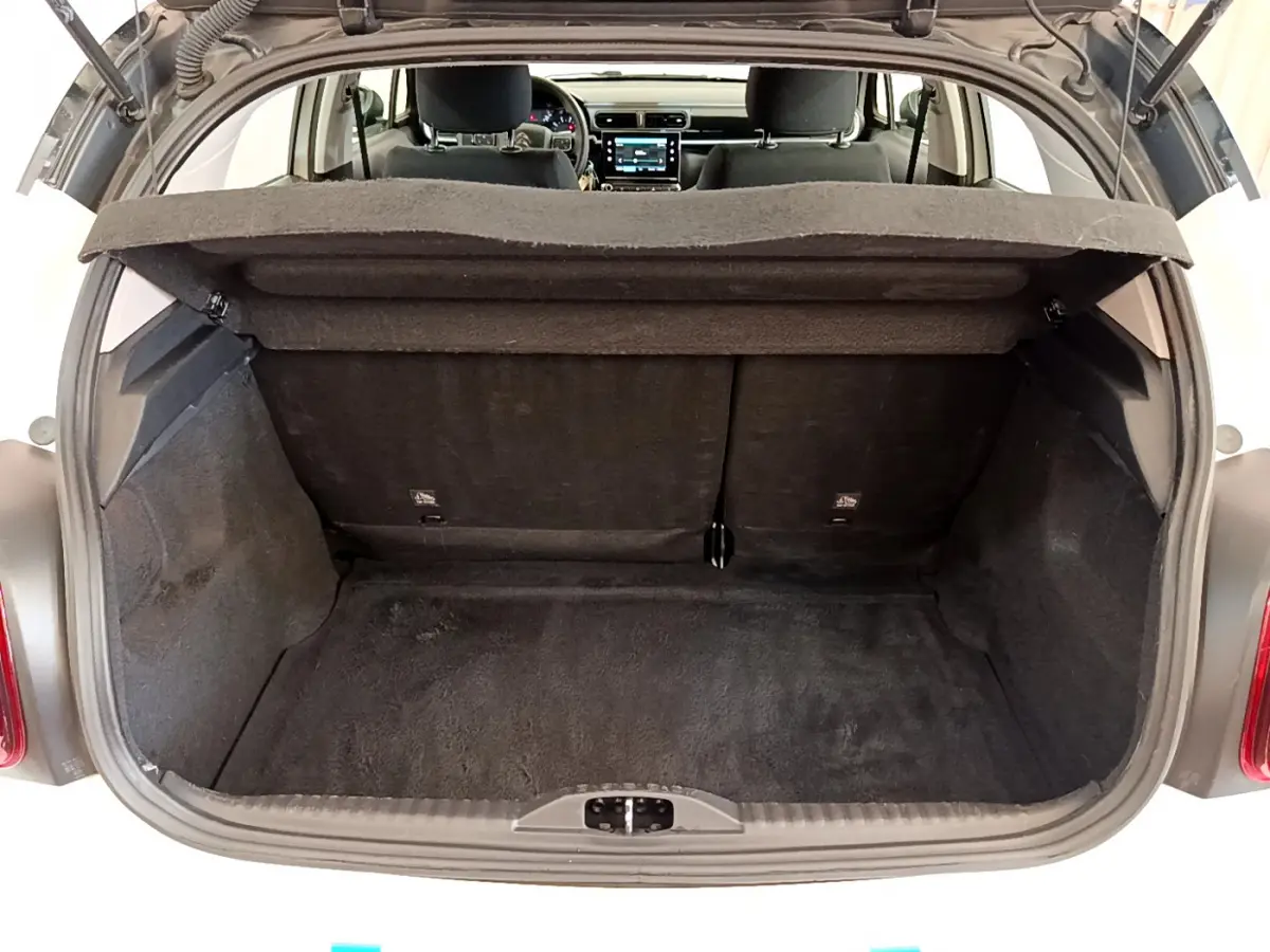 Coffre ouvert d'une Citroën C3 blanche vue de l'arrière, montrant l'espace de chargement et l'intérieur du véhicule.