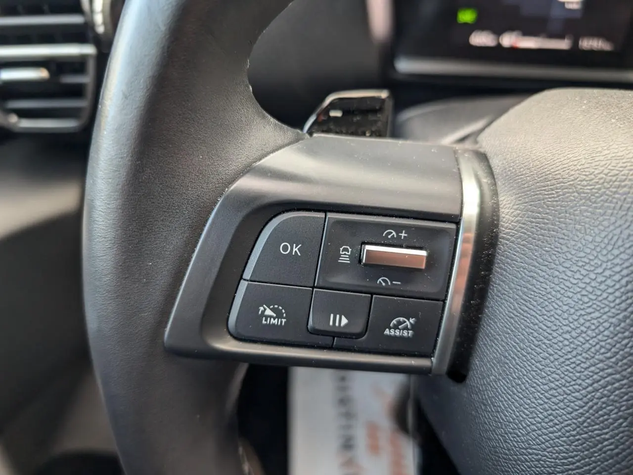 Gros plan sur les commandes de régulateur et assistant de conduite au volant cuir du Citroën C4 rouge foncé 2024.