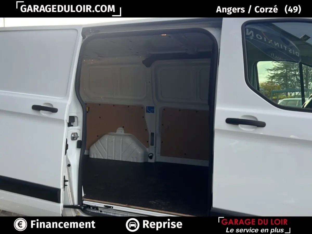 Vue latérale du fourgon blanc Ford Transit Custom avec porte coulissante ouverte montrant l'espace de chargement vide