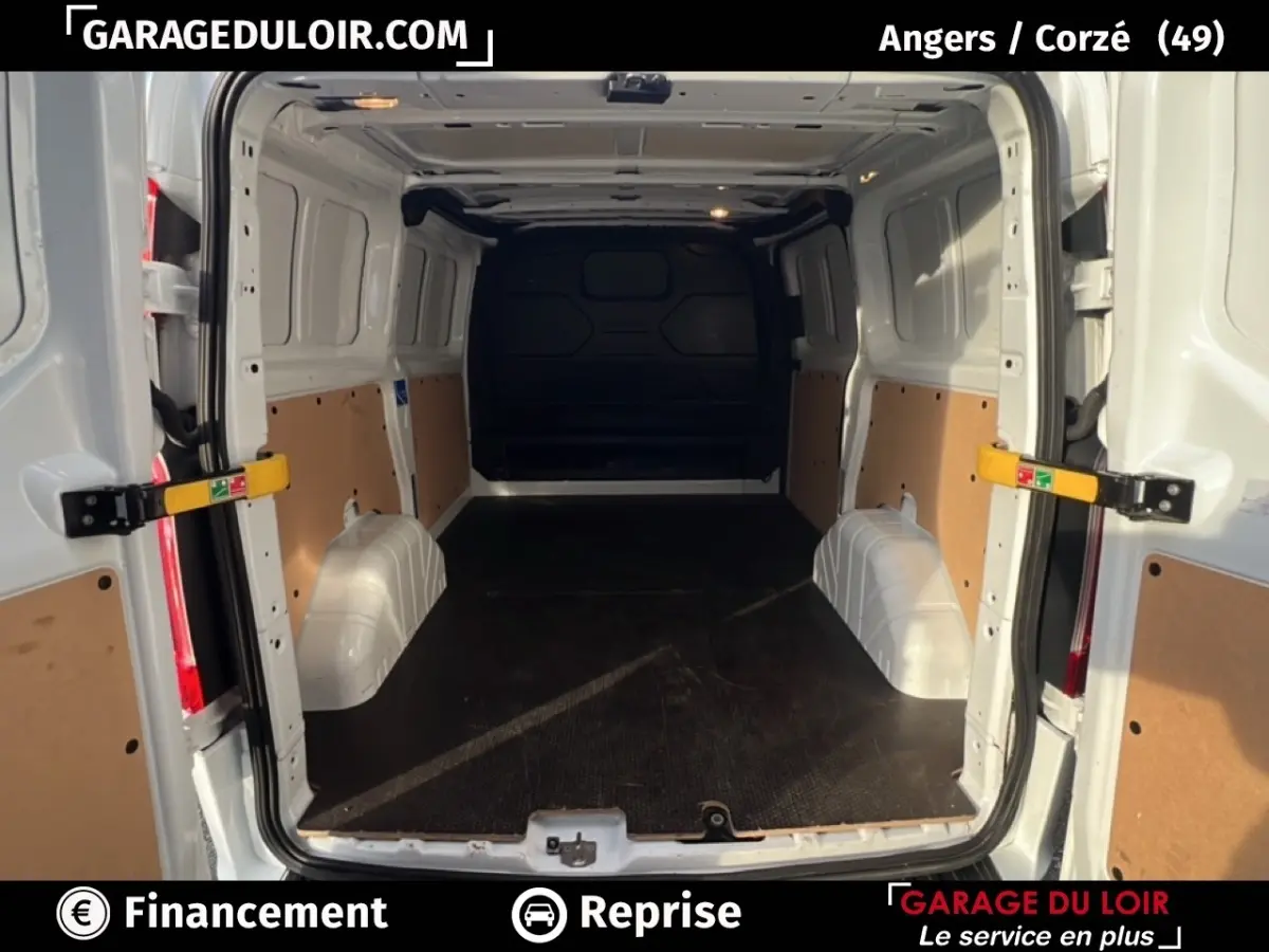 Vue intérieure arrière du fourgon Ford Transit Custom blanc, montrant l'espace de chargement vide avec cloison pleine noire.