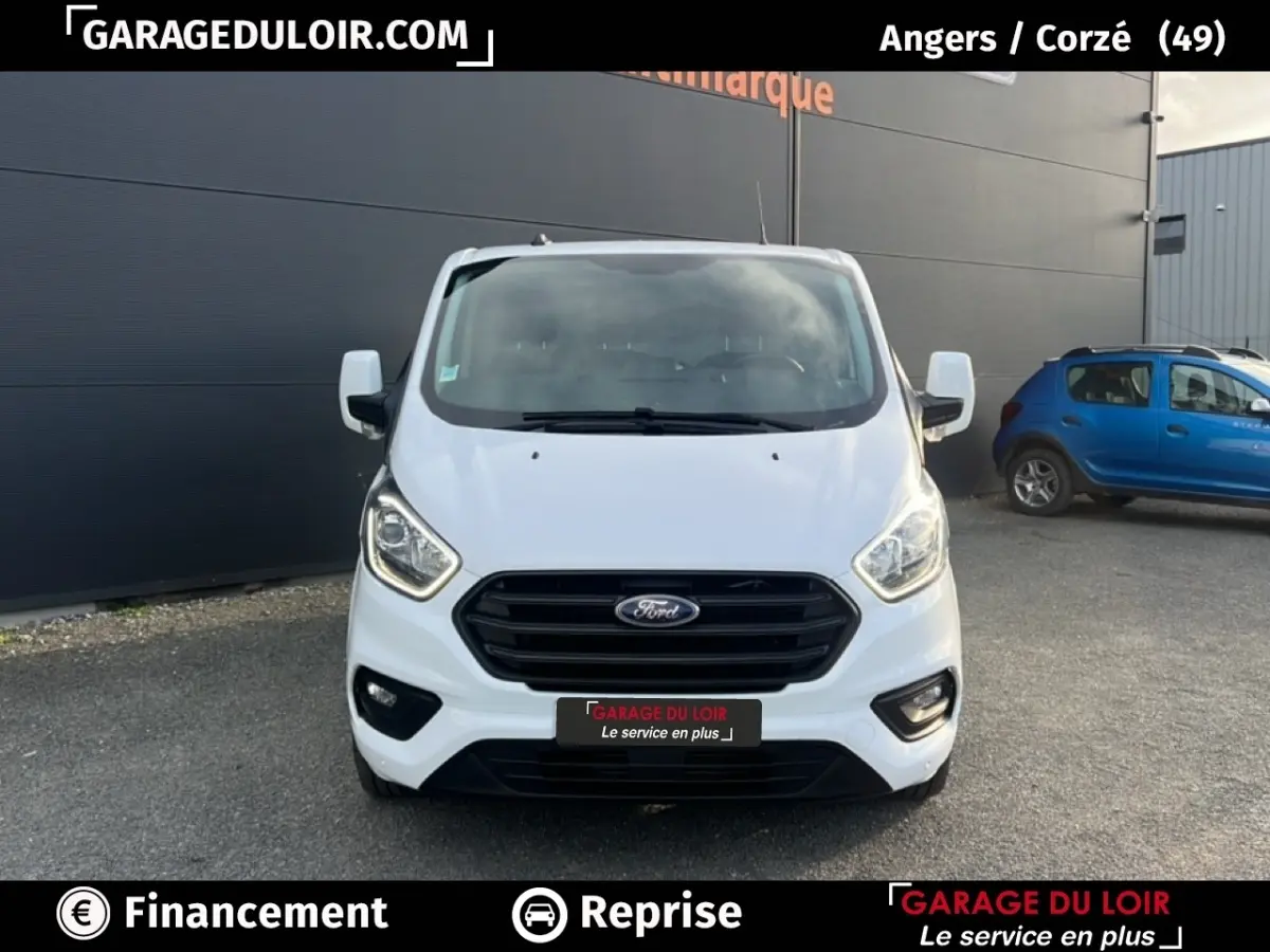 Vue frontale du Ford Transit Custom fourgon blanc 2023 avec calandre noire et feux LED allumés.