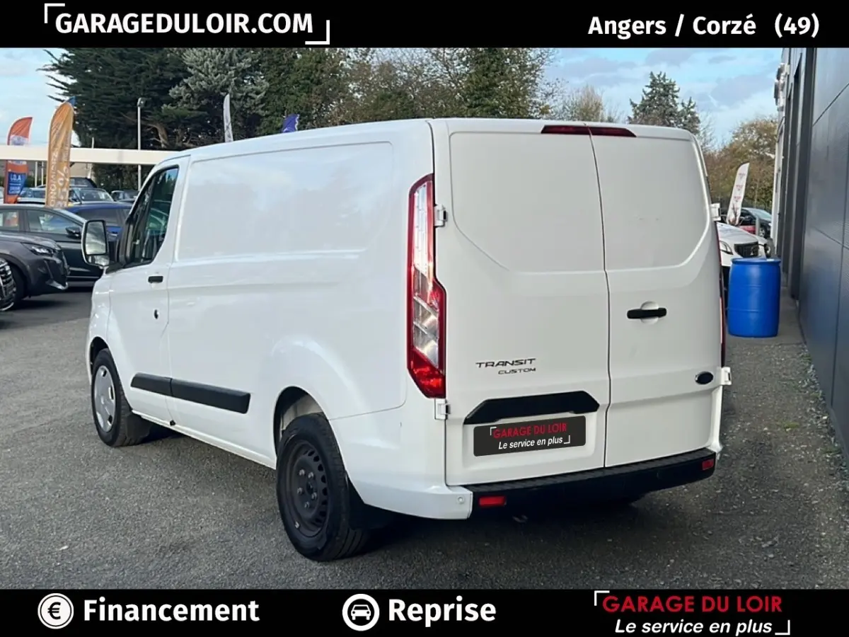 Vue 3/4 arrière droite d'un Ford Transit Custom blanc stationné, avec portes arrière fermées et jantes acier noires.