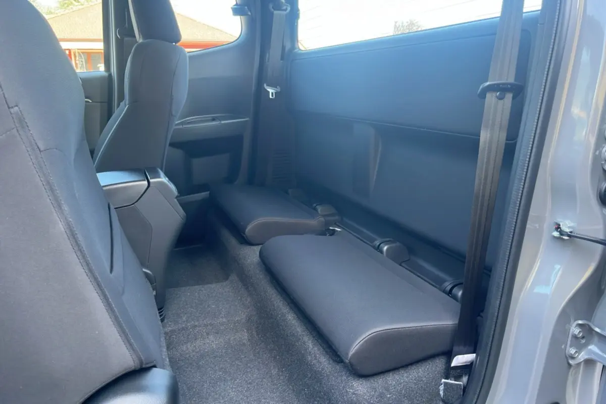 Vue intérieure côté droit du pick-up Isuzu D-MAX 2026 gris Kinabalu, montrant les sièges arrière rabattus en tissu noir.