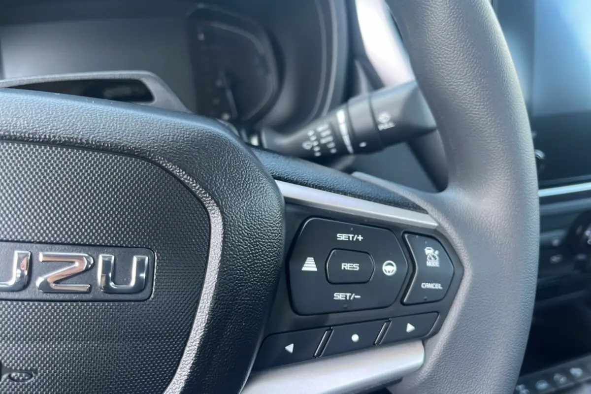 Gros plan sur le volant multifonctions noir de l'Isuzu D-MAX 2026, mettant en valeur les commandes de régulateur de vitesse.