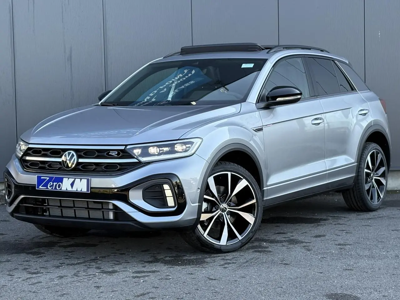 Volkswagen T-Roc gris pyrite en 3/4 avant droit avec jantes alliage 19" Misano et toit ouvrant ouvert.