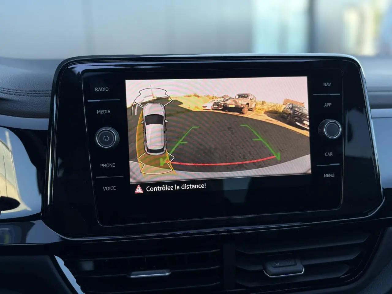 Écran central du Volkswagen T-Roc 2025 affichant la caméra de recul avec alertes de distance en intérieur noir brillant.