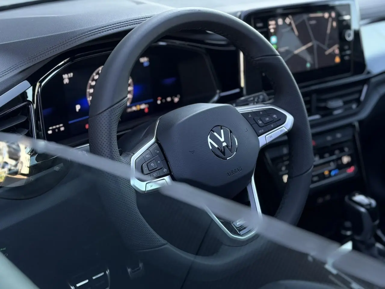 Volant multifonction noir avec logo Volkswagen au centre, tableau de bord digital et écran tactile du Volkswagen T-Roc 2025.