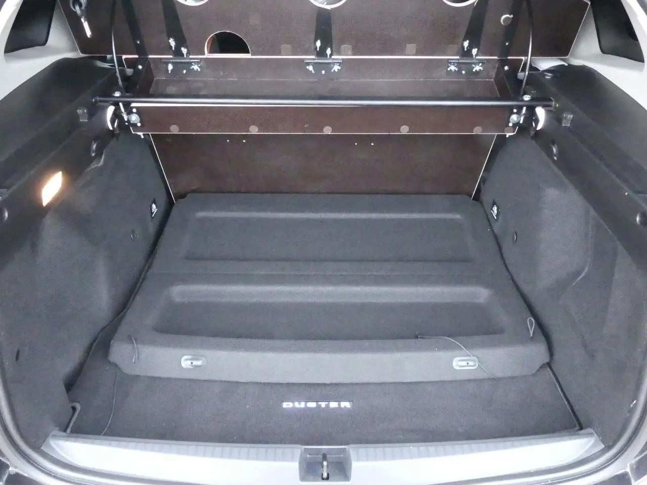 Coffre ouvert du Dacia Duster noir 2023, vue arrière montrant le tapis avec logo Duster et cache-bagages intégré.