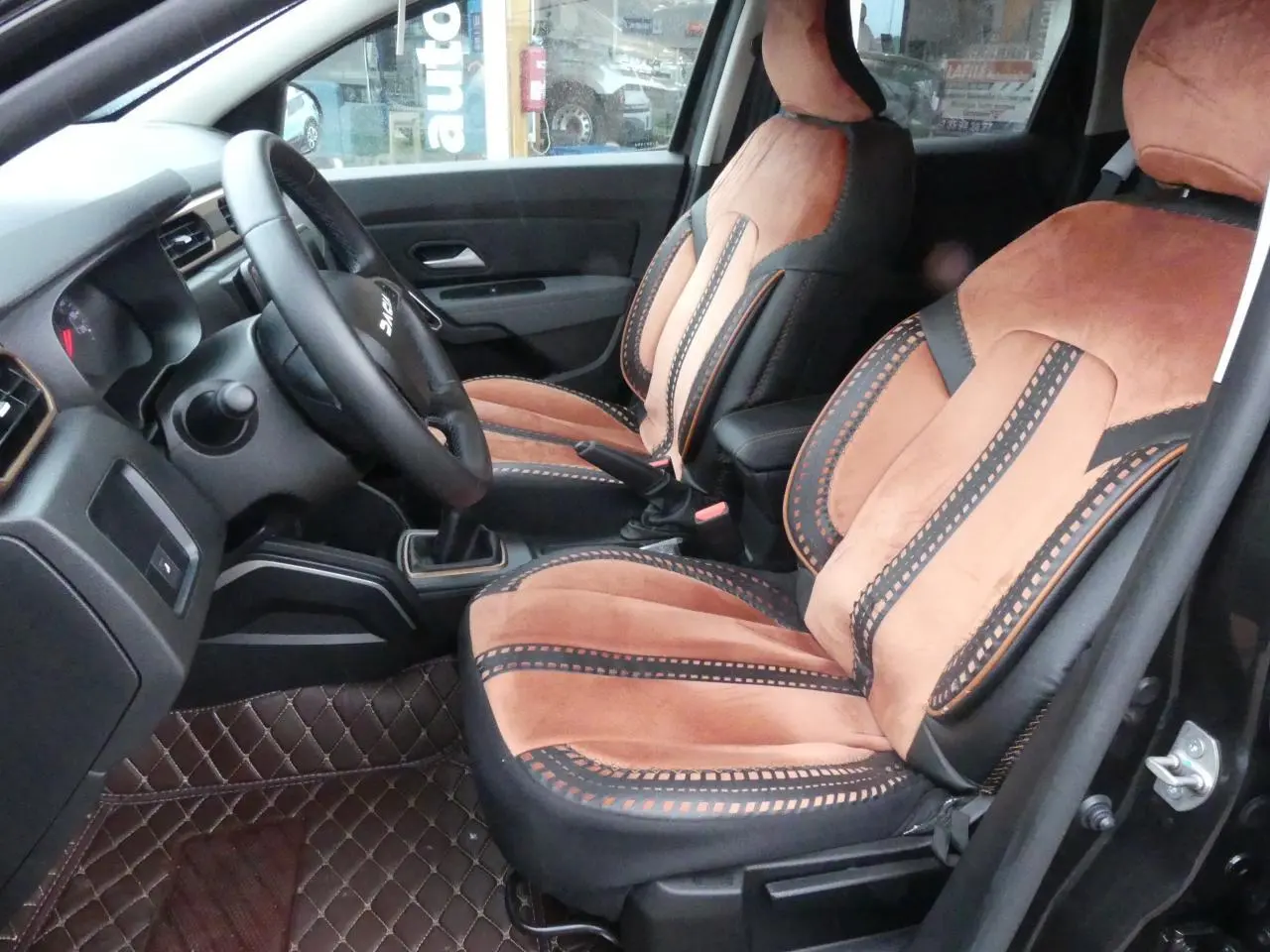 Intérieur du Dacia Duster 2023 version Extreme, vue côté conducteur, sièges marron et noir avec surpiqûres décoratives.