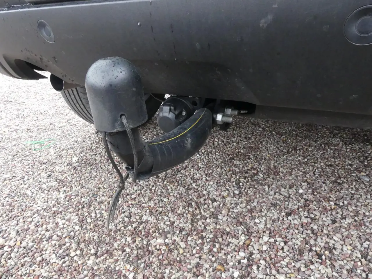 Gros plan sur l'attelage fixe noir sous le pare-chocs arrière d'un Dacia Duster noir 2023.