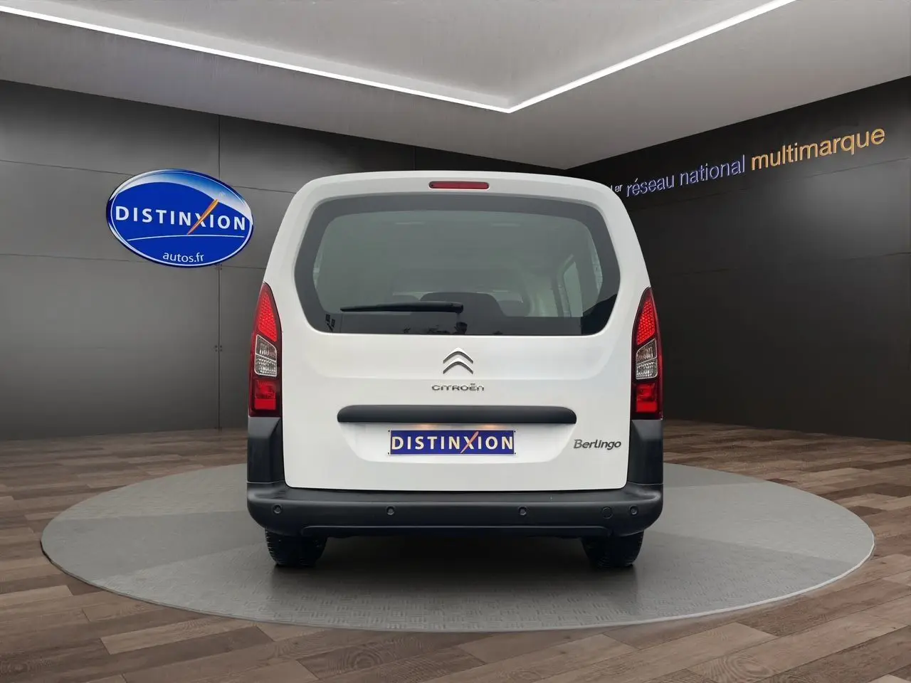 Vue arrière d'un Citroën Berlingo blanc 2018 avec hayon vitré et logo Distinxion visible en arrière-plan.