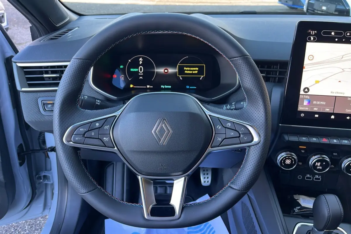 Vue intérieure centrée sur le volant cuir multifonctions de la Renault Clio V E-Tech 145 Esprit Alpine gris schiste.