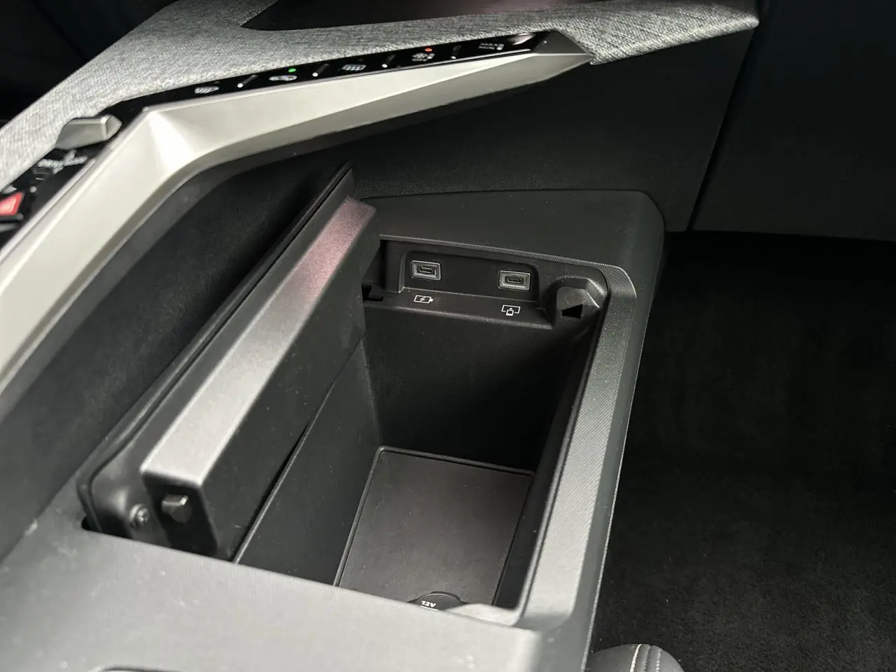 Gros plan sur la console centrale du Peugeot 3008 Hybrid 2024 avec ports USB-C et prise 12V intégrés.