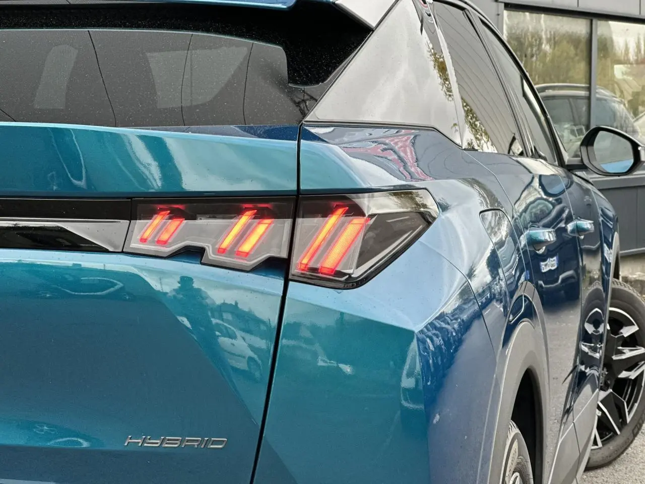 Feu arrière droit allumé sur Peugeot 3008 Hybrid 2024 bleu Obsession, vue 3/4 arrière côté droit.