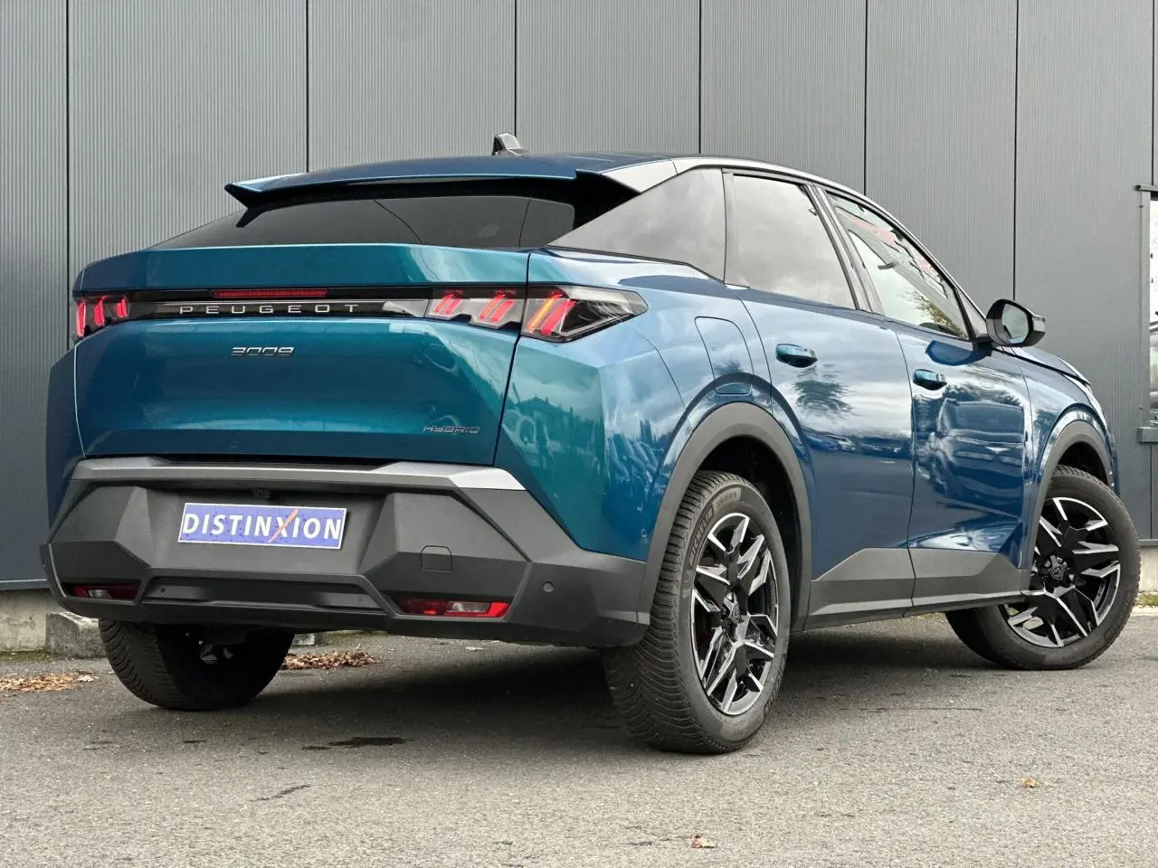 Vue 3/4 arrière droite du Peugeot 3008 Hybrid bleu Obsession avec feux arrière LED à 3 griffes et jantes alliage 19 pouces.