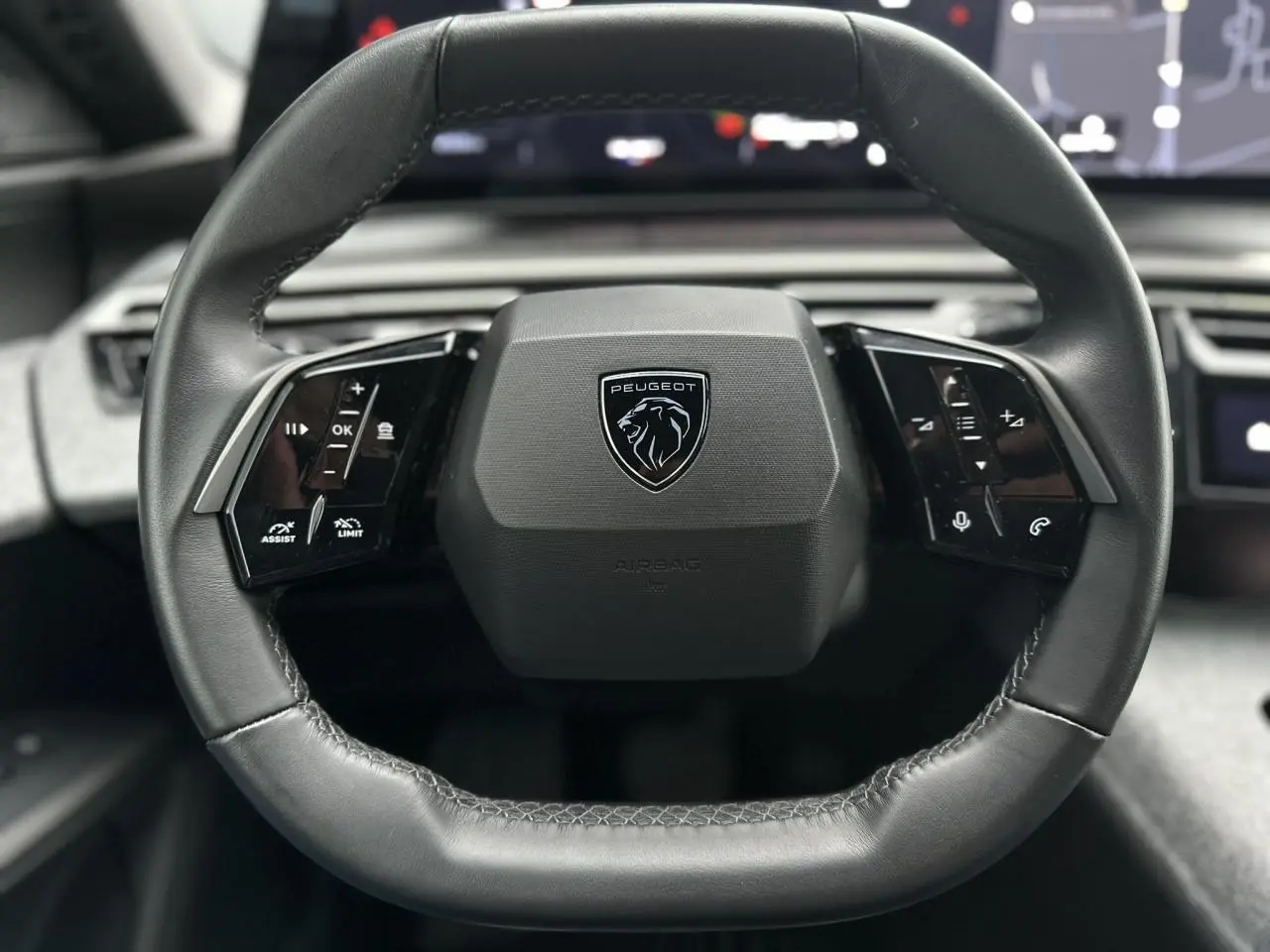 Volant compact cuir noir avec logo Peugeot au centre, vue rapprochée de l'intérieur du 3008 Hybrid 2024.