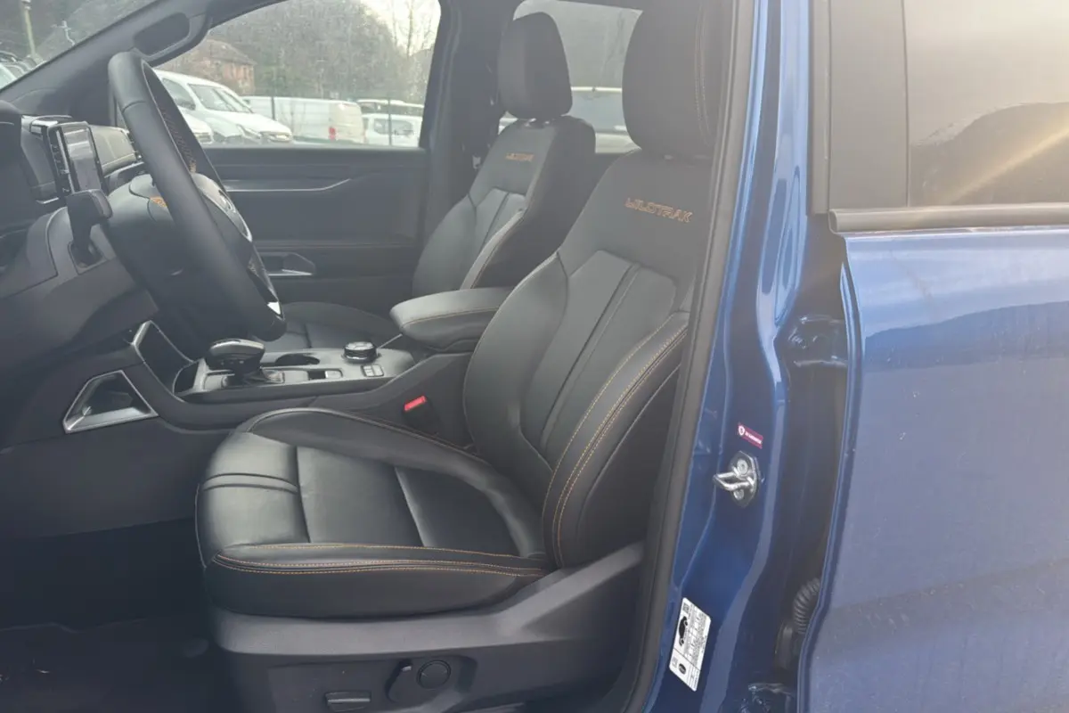Vue intérieure côté conducteur du Ford Ranger Wildtrak 2025 bleu lightning, sièges cuir noirs avec surpiqûres orange.