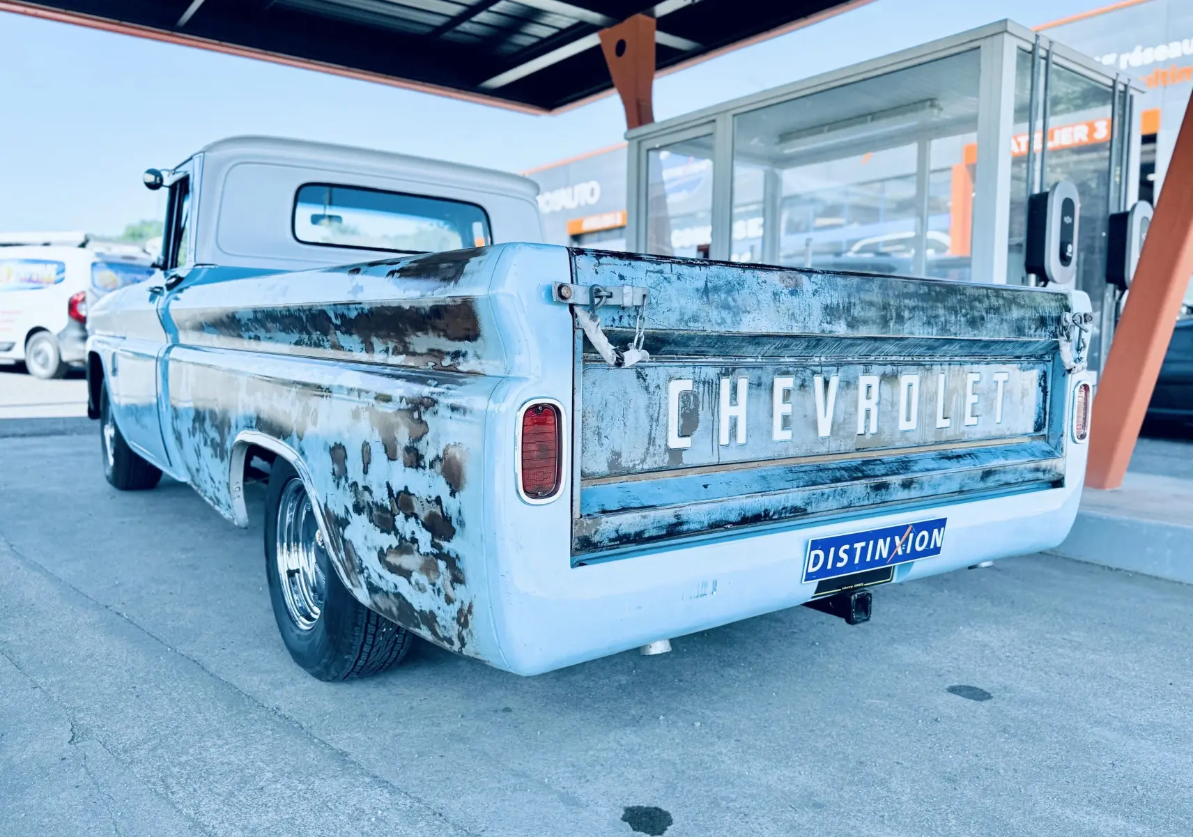 Vue 3/4 arrière droite du pick-up Chevrolet C10 Apache 1963 bleu patiné avec marquage CHEVROLET visible sur la benne.