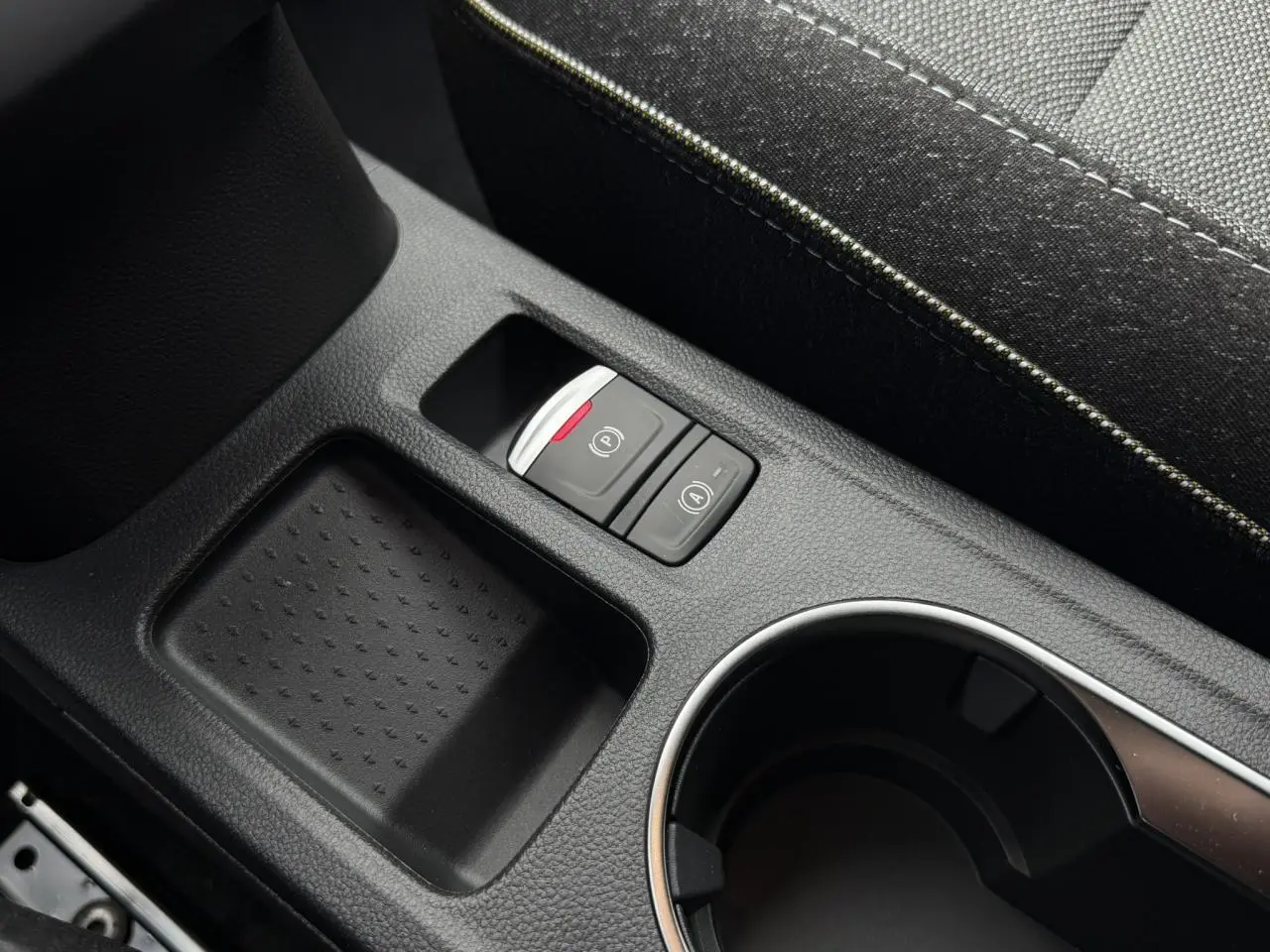 Gros plan sur la console centrale noire du Renault Captur 2026, avec boutons frein de parking électrique et auto hold.