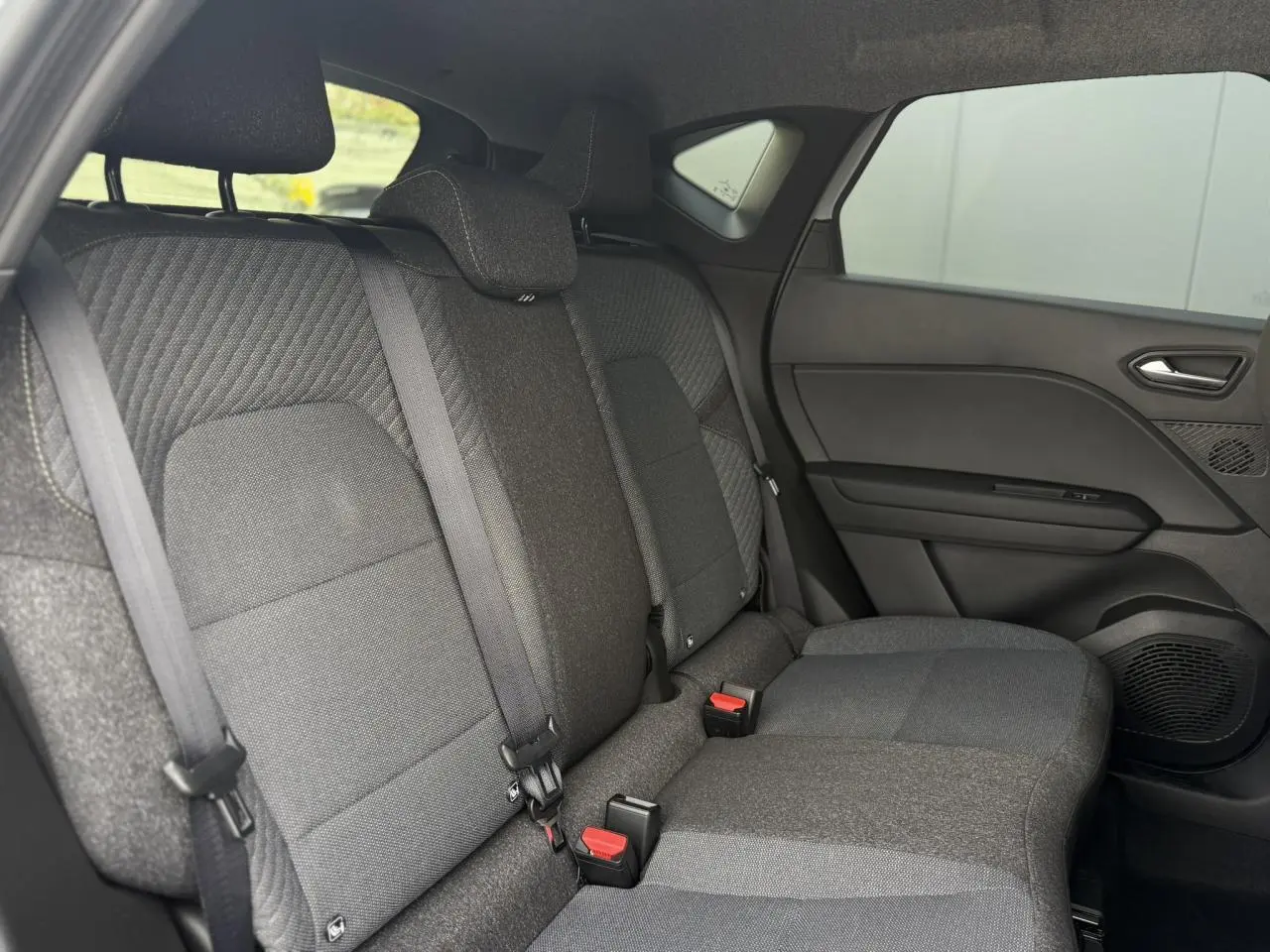 Vue intérieure côté droit des sièges arrière en tissu gris du Renault Captur 2026 version hybride avec ceinture de sécurité.