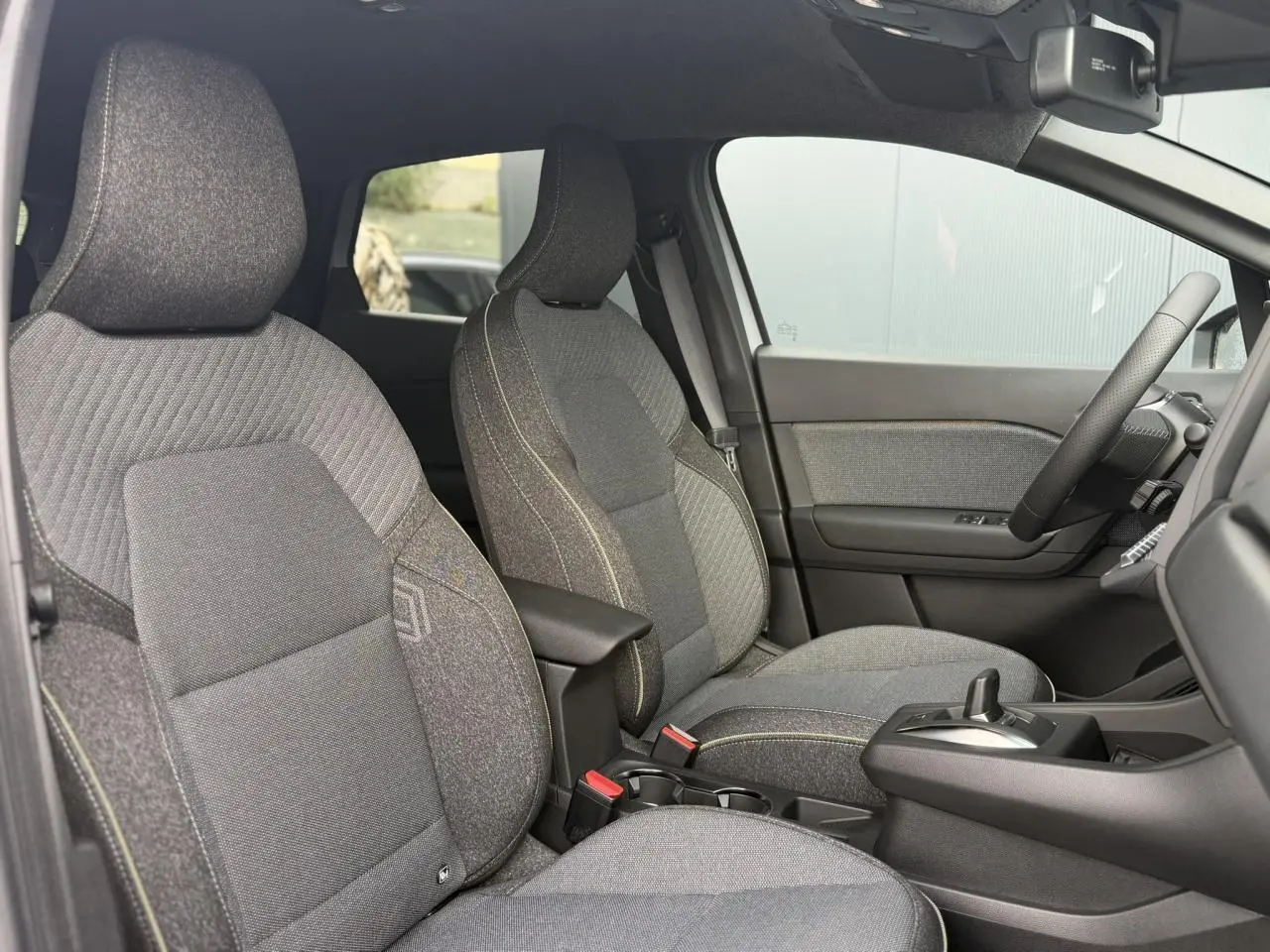 Vue intérieure côté droit du Renault Captur gris Rafale, mettant en valeur les sièges tissu et la console centrale avec accoudoir.