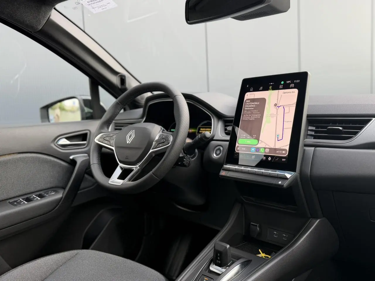 Vue intérieure côté conducteur du Renault Captur gris, avec volant multifonction et grand écran tactile vertical au tableau de bord.